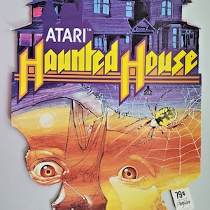 May include: Vintage Atari "Haunted House" game advertisement. The artwork features a purple haunted house, a spider, and a spooky face. The Atari logo and game title are in yellow and orange.