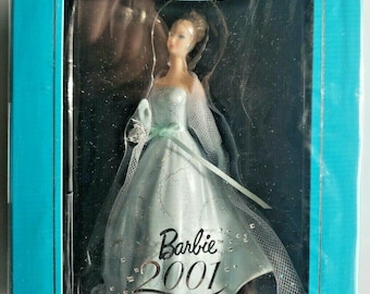 Könnte beinhalten: Hallmark Keepsake Ornament mit einer Barbie-Puppe in einem hellblauen Kleid. Die Puppe hat blondes Haar und trägt ein langes, fließendes Kleid. Das Ornament befindet sich in einer türkisfarbenen Box und trägt die Aufschrift "Barbie 2001".