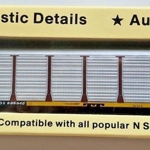 May include: A model train car in a box. The box is yellow with text that reads "Realistic Details" and "Authentic Colors." The train car is brown and silver with the text "TRAILER TRAIN." The box also says "Compatible with all popular N Scale brands."