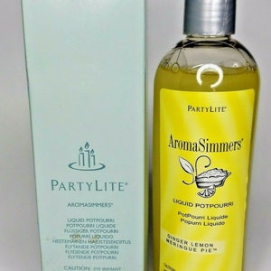 May include: A yellow and white bottle of PartyLite AromaSimmers liquid potpourri in the scent Ginger Lemon Meringue Pie. The bottle is 11.8 fluid ounces or 350 milliliters.
