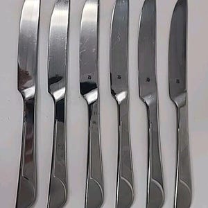 May include: Set of six silver dinner knives with a curved handle and a slightly pointed tip.