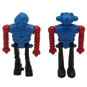 May include: Two small, plastic robot figures. Each robot has a blue head and torso, red arms, and black legs. The robots are standing upright, with their arms at their sides. The robots are toys.