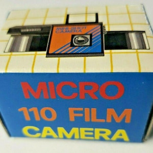 May include: A blue and white box with the text "MICRO 110 FILM CAMERA" printed on the front. The box features a picture of a black and orange camera with the text "MINI SHOT CAMERA" printed on the front.