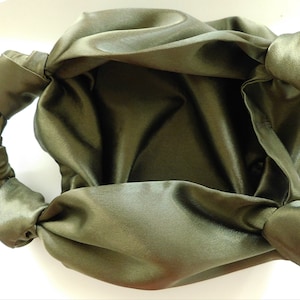 Pu&ograve; includere: Una borsa a mano in satin verde con un manico annodato. La borsa &egrave; realizzata in tessuto morbido e fluido e ha un design semplice ed elegante.