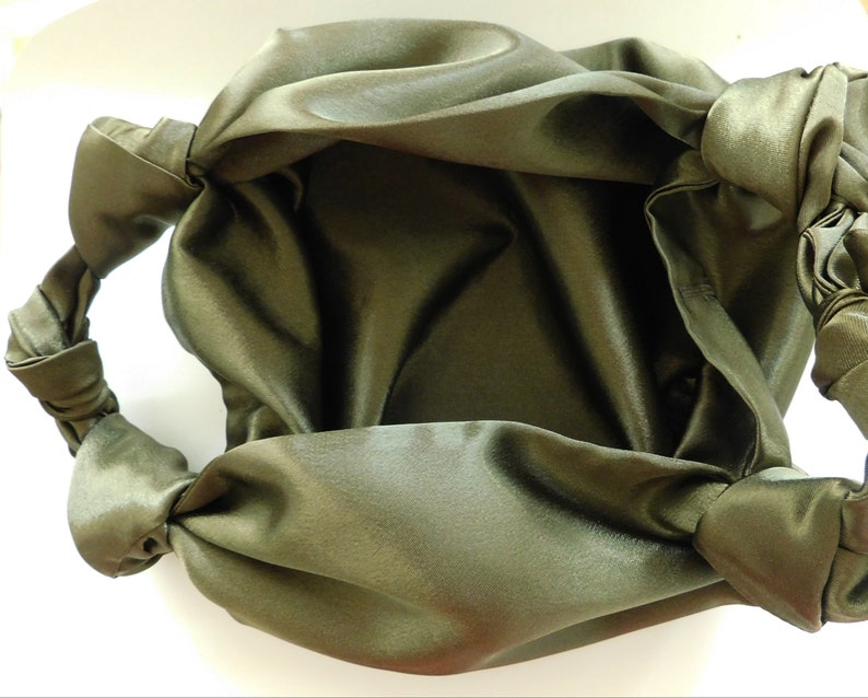 Pu&ograve; includere: Una borsa a mano in satin verde con un manico annodato. La borsa &egrave; realizzata in tessuto morbido e fluido e ha un design semplice ed elegante.