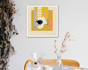 May include: A square wall art print featuring a mustard yellow background with layered geometric shapes in white, gray, and a small pink accent. A central black circular element sits atop white abstract forms. The print is framed in a thin white border.
