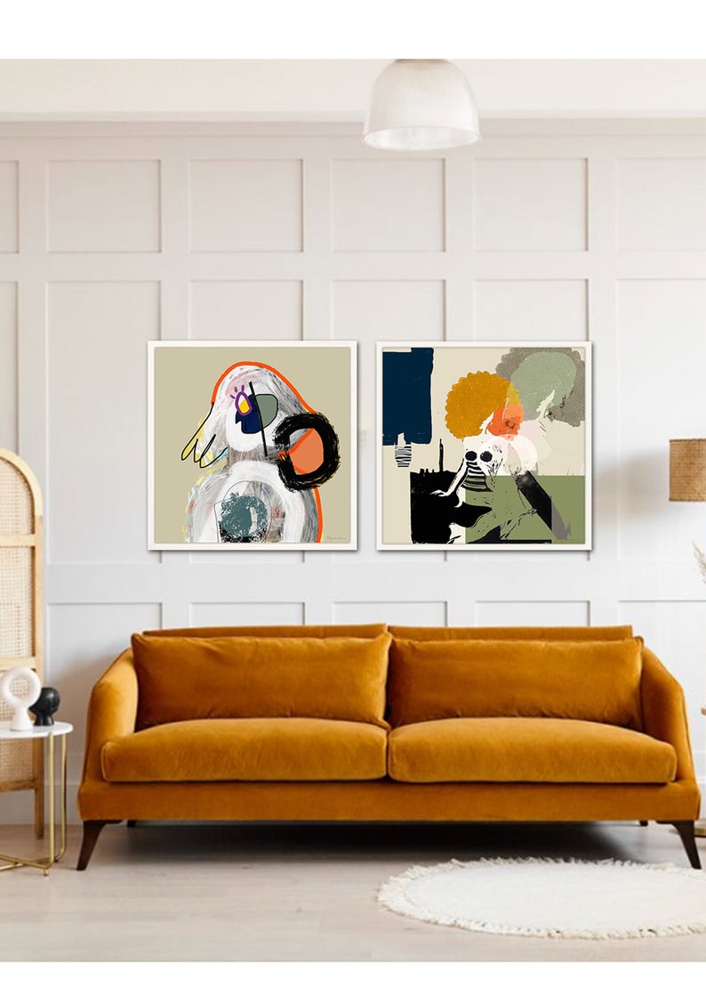 May include: Two framed abstract art prints featuring colourful geometric shapes and figures. The prints are hung on a white wall above a mustard yellow velvet sofa.