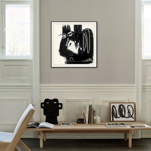 May include: Black and white abstract art print in a black frame. The print features a stylized face with bold lines and shapes.