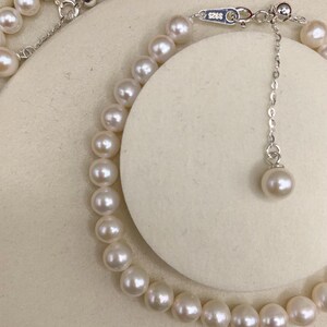 May include: A delicate pearl necklace with a silver clasp and adjustable chain. The necklace features numerous round, creamy white pearls. The clasp is marked with "S925". The necklace is displayed on a neutral background.