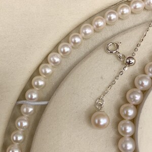 May include: A delicate pearl necklace with a matching pendant. The necklace features a strand of lustrous, round pearls. The pendant hangs from a fine silver chain. The pearls have a soft, creamy white color.
