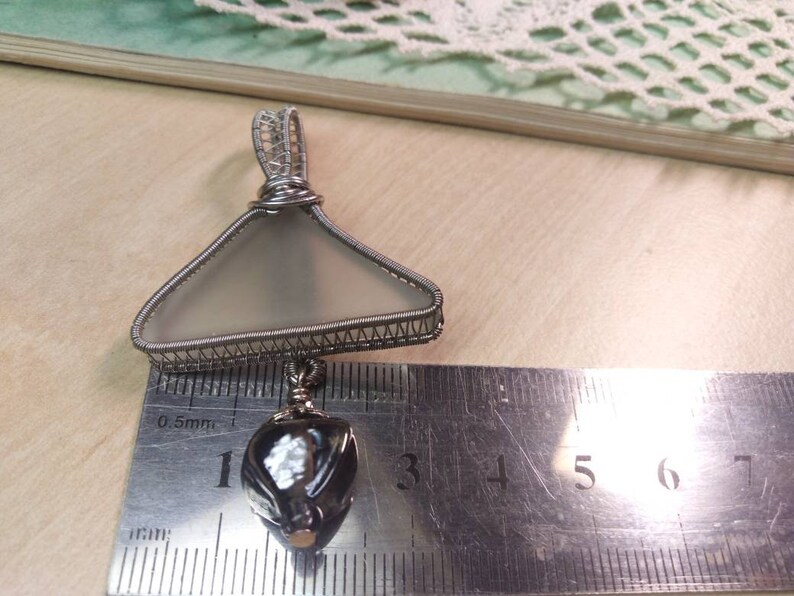 Unique triangular pendant with a pale sea glass wrapped in silver coated copper wire and a smokey glass bead dangling under.
