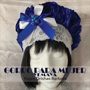 May include: Blue satin flower crown with a white lace trim and a blue and white bow with a blue jewel accent. The text "GORRO PARA MUJER YEMAYA" and "Trajes Orishas Barbara" is printed below the crown.