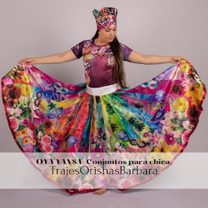 May include: A woman wearing a colourful, floral print skirt and a matching top with a white headband. The skirt is a full circle skirt with a rainbow stripe pattern. The text "OYA YANSA: Conjuntos para chica. TrajesOrishasBarbara" is at the bottom of the image.