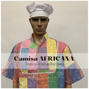 May include: A colorful, patchwork shirt with a white chef's hat. The shirt has a variety of colors, including red, yellow, green, blue, and purple. The text "Camisa AFRICANA" and "TrajesOrishasBarbara" is printed on the shirt.