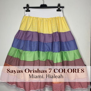May include: A colorful, tiered skirt with a white waistband and a variety of gingham patterns in yellow, purple, blue, green, brown, pink, and red. The skirt is hanging from a black hanger.
