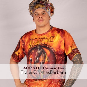 May include: A person wearing a white and gold patterned head covering and a bright orange, yellow, and red t-shirt with a graphic of a person and the text "AGGAYU". The text "AGGAYU: Camisetas TrajesOrishasBarbara" is at the bottom of the image.