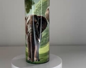 May include: A cylindrical tumbler featuring a detailed graphic of an elephant standing in a lush green forest. The tumbler is positioned on a white circular rotating display stand with a visible power switch and a DC-5V port on the front base.