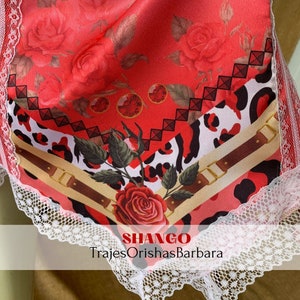 May include: A red, white, and black fabric with a leopard print and a rose design. The fabric has a white lace trim and the text "SHANGO TrajesOrishasBarbara" at the bottom.