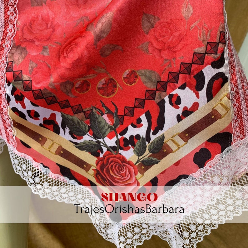 May include: A red, white, and black fabric with a leopard print and a rose design. The fabric has a white lace trim and the text "SHANGO TrajesOrishasBarbara" at the bottom.