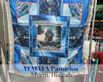 May include: A blue and white patterned fabric with a ship, mermaid, and chain design. The fabric has the text "YEMAYA: Pañuelos Miami. Hialeah" printed on it.