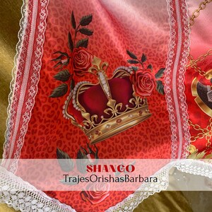 May include: A red and gold crown with a red rose and green leaves on a red and white leopard print background. The text "SHANGO" and "TrajesOrishasBarbara" is at the bottom of the image.