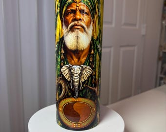 May include: A cylindrical tumbler featuring a vibrant graphic print of an older person with a white beard wearing a green turban with a gold jewel. Below the portrait is an elephant head illustration and a circular yin-yang symbol.