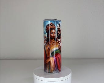 May include: A cylindrical tumbler featuring a vibrant, full-wrap graphic of a Black queen wearing an ornate gold crown and jewelry, standing beside a Black king wearing a white crown. The design includes rich red, gold, and blue color tones.