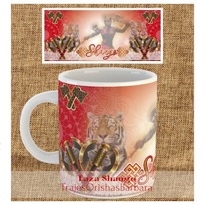 May include: White ceramic mug with a red, orange, and yellow design featuring a tiger, two axes, and the text "Taza Shango Trajes Orishas Barbara".