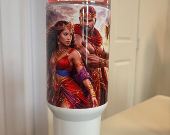 May include: A white cylindrical tumbler featuring a vibrant graphic print of a royal couple in ornate red and gold attire. The tumbler has a clear lid with a red accent and includes a metal straw. The design depicts a man and woman with crowns.