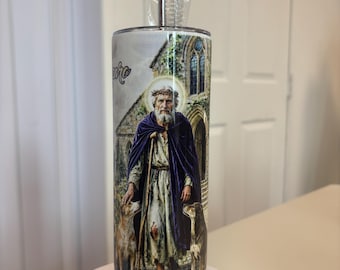 May include: A cylindrical stainless steel tumbler featuring a full-wrap graphic of a bearded figure wearing a purple cloak and a crown of thorns, standing with two dogs in front of a stone building. A metal straw and cleaning brush are included.
