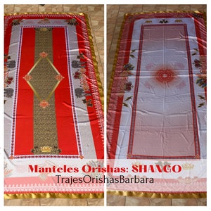 May include: A red and white tablecloth with a gold trim and a diamond pattern in the center. The tablecloth has a design of a crown and other symbols. The text "Manteles Orishas: SHANGO" and "TrajesOrishasBarbara" is printed on the tablecloth.