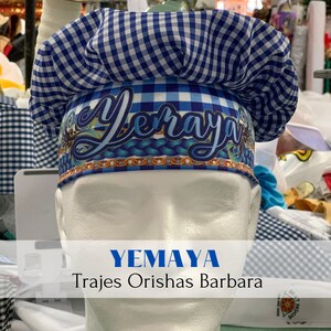 May include: A blue and white checkered chef's hat with the name "Yemaya" printed on the front. The hat is on a white mannequin head. The text "YEMAYA Trajes Orishas Barbara" is printed below the hat.
