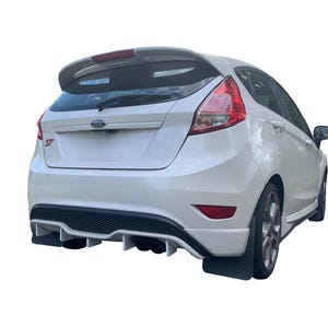 May include: White Ford Fiesta ST hatchback with a rear spoiler and a black rear diffuser. The car has a black and white grille and a black rear bumper.