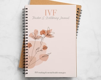 May include: A pink and brown spiral bound journal with the title "IVF Tracker & Wellbeing Journal" and the text "IVF tracking & mental health strategies". The cover features a line drawing of a flower with brown stems and pink and brown leaves.