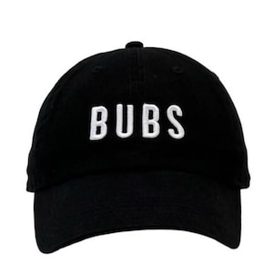 May include: Black baseball cap with the word "BUBS" embroidered in white block letters across the front. The cap has a curved brim and a rounded crown.