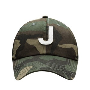 May include: A camouflage baseball cap with a white felt letter 'J' on the front.