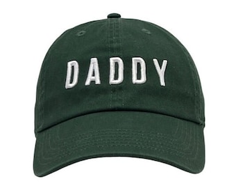 May include: A dark green baseball cap with the word "DADDY" embroidered in white on the front.
