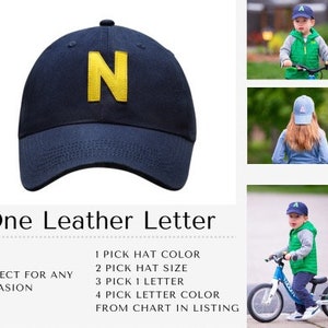 May include: A navy blue baseball cap with a yellow felt letter N. The cap is shown on a white background. One Leather Letter. Perfect for any occasion. 1 Pick Hat Color. 2 Pick Hat Size. 3 Pick 1 Letter. 4 Pick Letter Color from chart in listing.