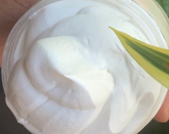 May include: Close-up of a white creamy substance in a clear jar. The cream is thick and smooth, with a swirl pattern on top.