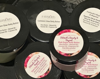 May include: A collection of six black and white jars with labels containing the name "Fatimoh's Beauty & Beyond" and descriptions of different body butters. The jars are filled with a white cream and have black lids.