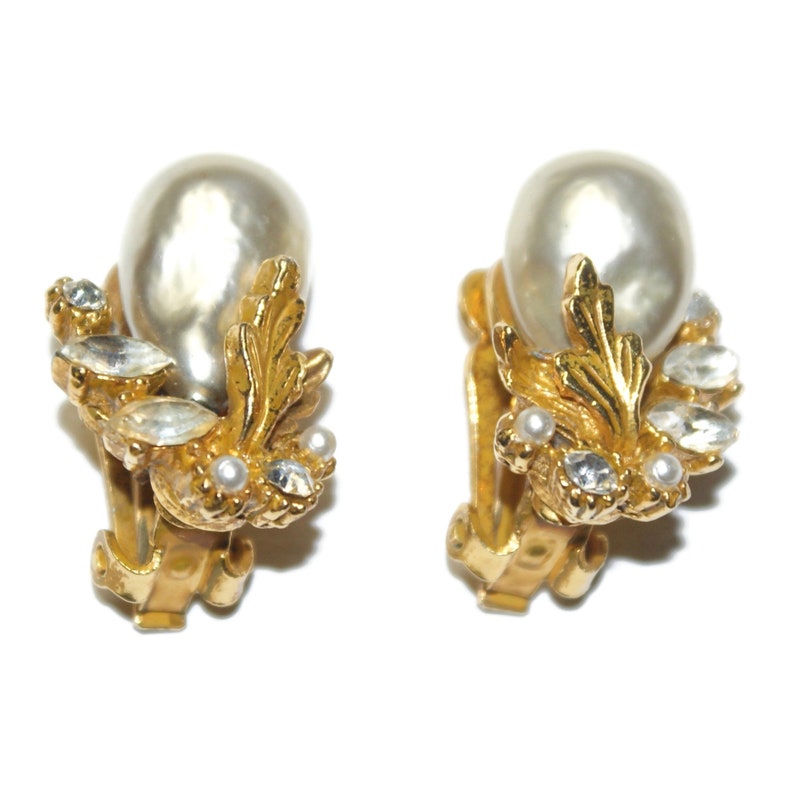 May include: A pair of gold tone clip-on earrings with faux pearl drops and clear rhinestone accents.