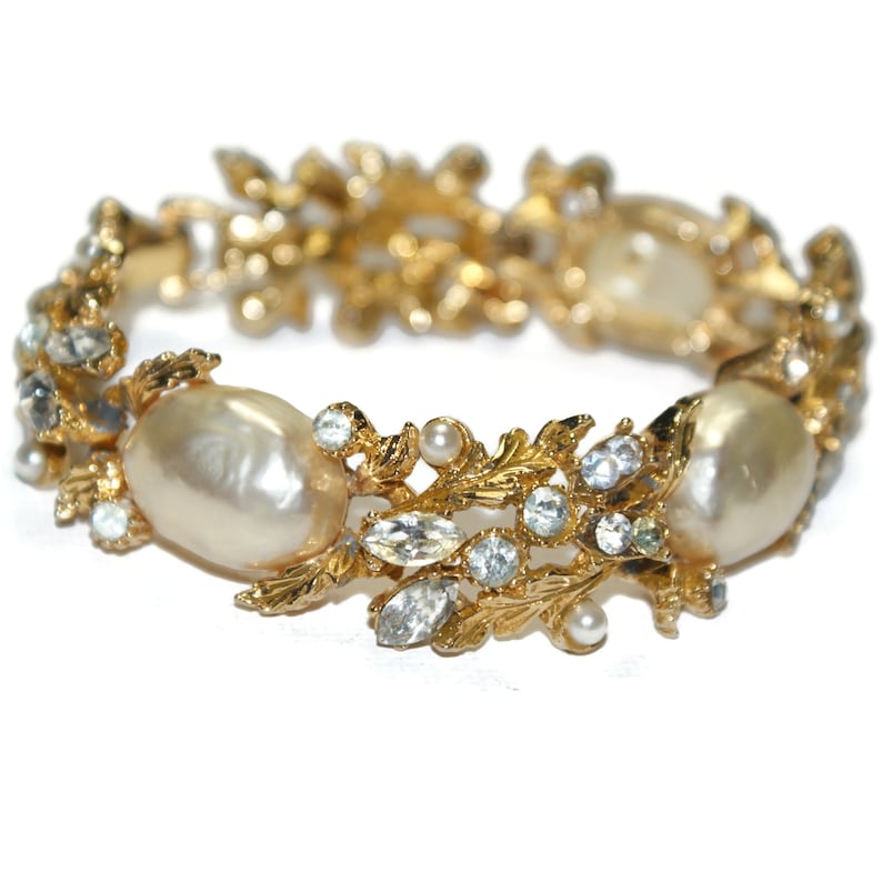 May include: A gold bracelet with faux pearls and rhinestones in a leaf design.