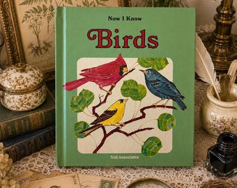 May include: A green hardcover book titled Now I Know Birds by Troll Associates. The cover features a central illustration of a red cardinal, a blue bird, and a yellow bird perched on brown branches with green leaves against a white background.