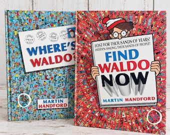 May include: Two Where's Waldo books by Martin Handford. The left book has a blue background with a white label reading Where's Waldo. The right book has a red background with an illustration of Waldo holding a sign reading Find Waldo Now.