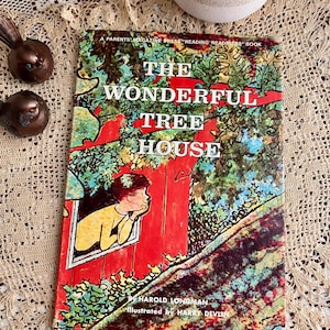 May include: A vintage children's book titled "The Wonderful Tree House" with a colorful illustration of a treehouse and a child looking out the window. The cover features text by Harold Longman and illustrations by Harry Devlin.