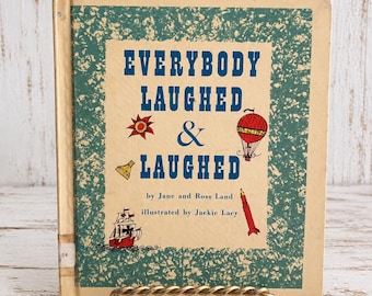 May include: A hardcover book titled Everybody Laughed & Laughed by Jane and Ross Land, illustrated by Jackie Lacy. The cover features a cream center with blue text, a red sun, a red hot air balloon, a ship, and a red rocket on a green border.