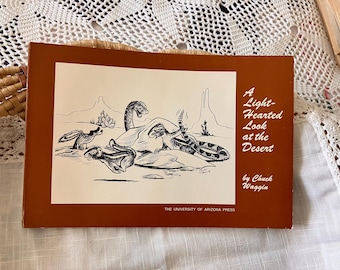 May include: A vintage book cover with a brown border and a black and white illustration of desert animals. The title reads "A Light-Hearted Look at the Desert" by Chuck Waggin. Published by The University of Arizona Press.