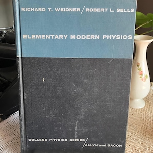 May include: A vintage hardcover book titled "Elementary Modern Physics" by Richard T. Weidner and Robert L. Sells. The book has a blue and black cover with white text. The book is part of the College Physics Series, published by Allyn and Bacon.