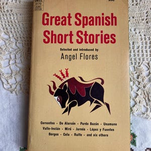 May include: A vintage paperback book titled "Great Spanish Short Stories" with red lettering on a tan cover. The cover features a black and burgundy illustration of a bull. The book is a Laurel Edition.