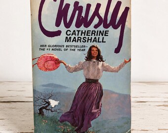 May include: A vintage paperback book titled Christy by Catherine Marshall, published by Avon. The cover features an illustration of a person in a white blouse and purple skirt holding a pink hat against a mountain landscape with the text $1.25.